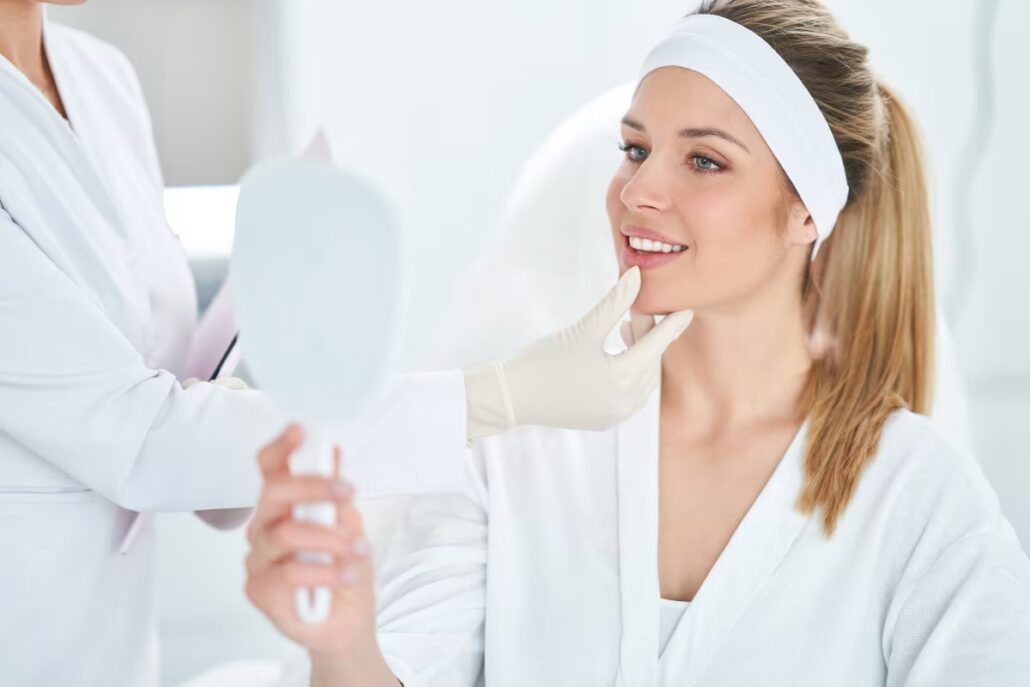 Smiling woman holding a mirror during a Botox consultation, illustrating the results and duration of treatment effects.