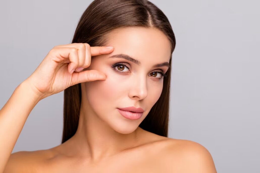 Woman lifting her brow to showcase the rejuvenating effects of a brow lift procedure.