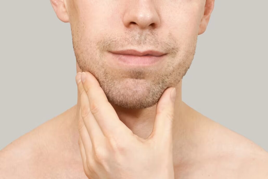 Close-up of a man touching his chin, illustrating chin implant options for augmentation.