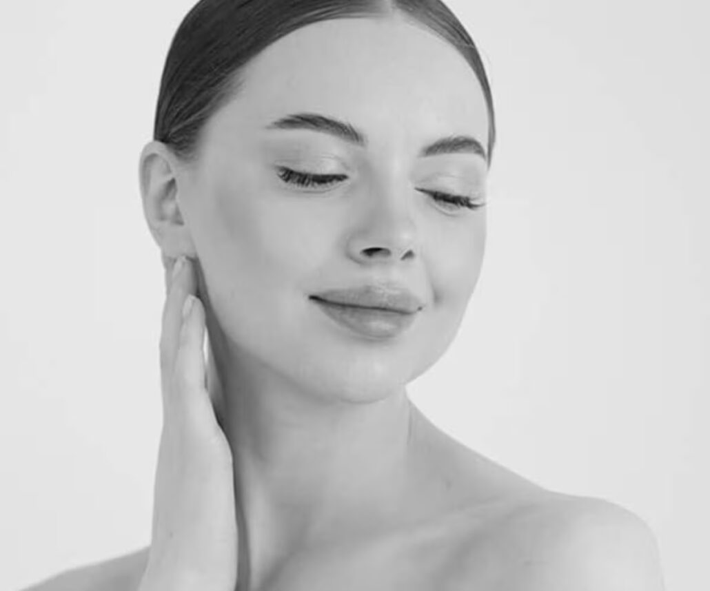 Woman with serene expression gently touching her neck, symbolizing balance between beauty and health in rhinoplasty.