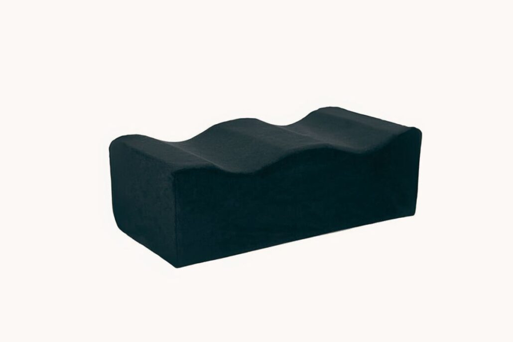 Black high-density BBL pillow designed to offload pressure from buttocks onto thighs during post-op sitting.